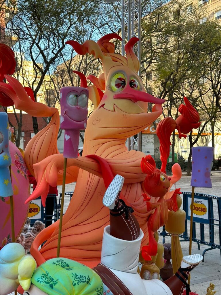 Falla infantil. Se ve un ninot de falla que es una llama de fuego con ojos, nariz y boca.